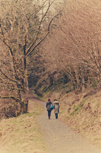 2 woman walking down country path through trees