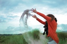 woman tossing sand in the air