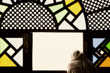 shrouded woman looking out stained glass windows