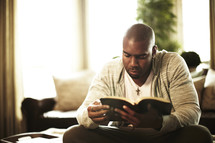 Man sitting, reading the bible at home