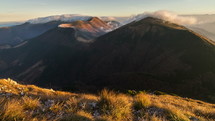 Clouds moving over alpine mountains ridge in sunny autumn nature at sunrise morning time-lapse
