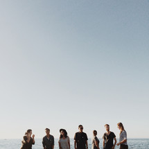 men and women standing outdoors in front of a view of the ocean 
