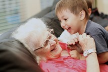 Young boy and grandmother laughing on couch