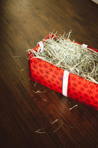 box of straw wrapped in Christmas paper - manger