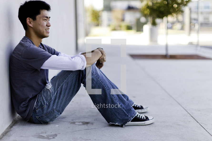 profile of a man sitting on a sidewalk