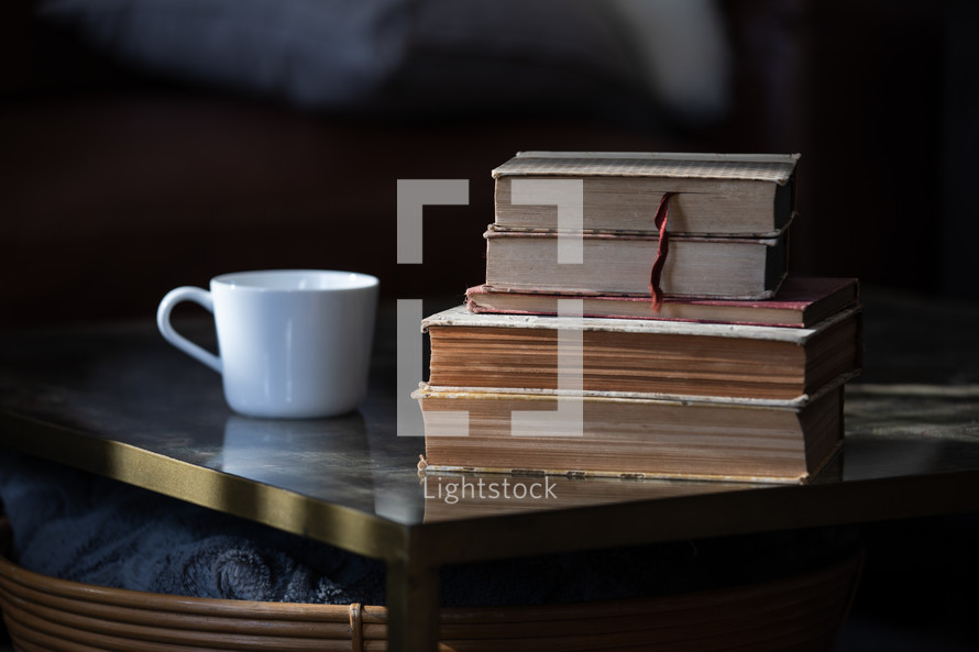 coffee cup and a stack of old books on a table 