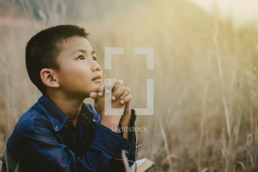 boy praying outdoors 