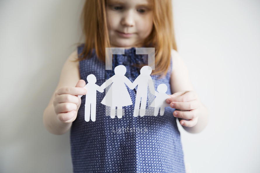 A little girl holds a paper cutout of a family.