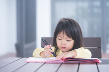 Cute little girl doing homework, reading a book