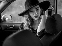 a woman in a hat sitting in a car 
