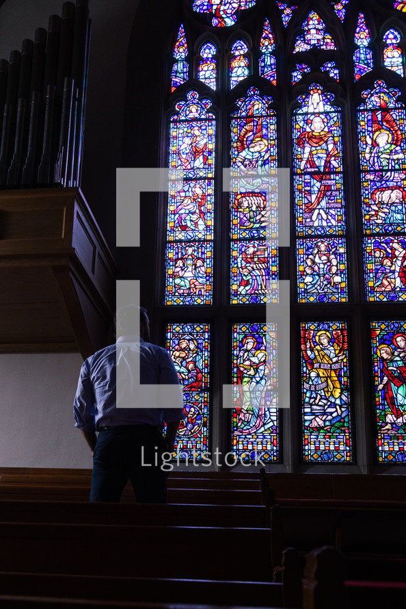a man standing in front of a stained glass window 