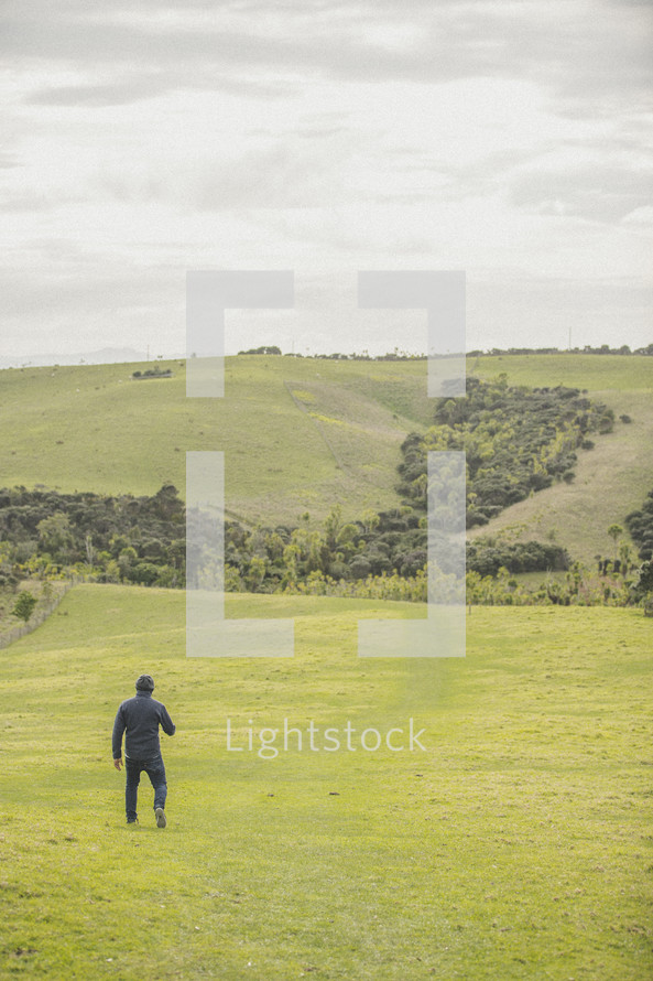 a man walking in a field of green grass 