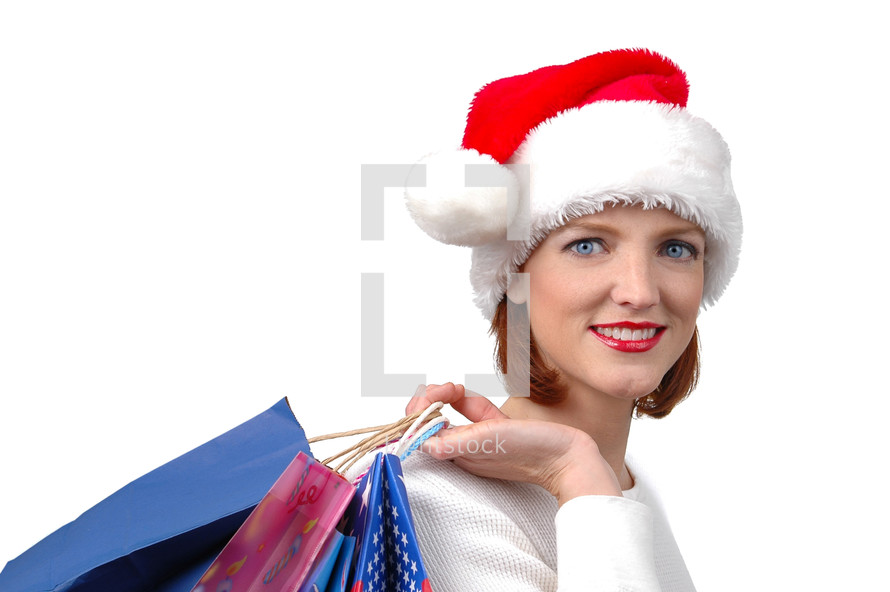 A woman in a Santa hat carrying shopping bags.