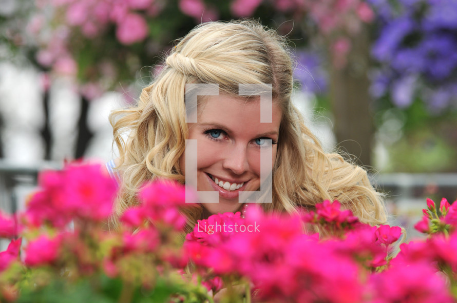 A woman smiling through pink flowers.
