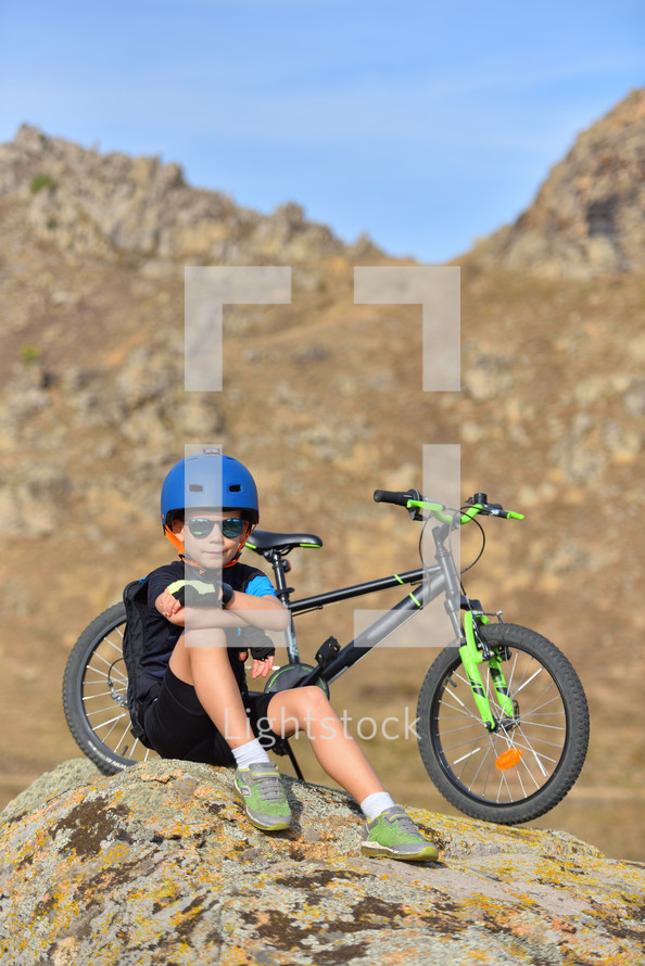  kid boy of 7 years having fun in autumn park with a bicycle on beautiful fall day. Active child wearing bike helmet