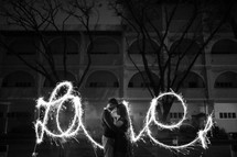 couple kissing in front of the word love in sparklers 