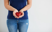a woman with cupped hands holding a red valentine heart 
