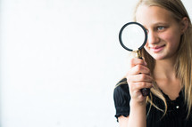 teen girl looking through a magnifying glass 