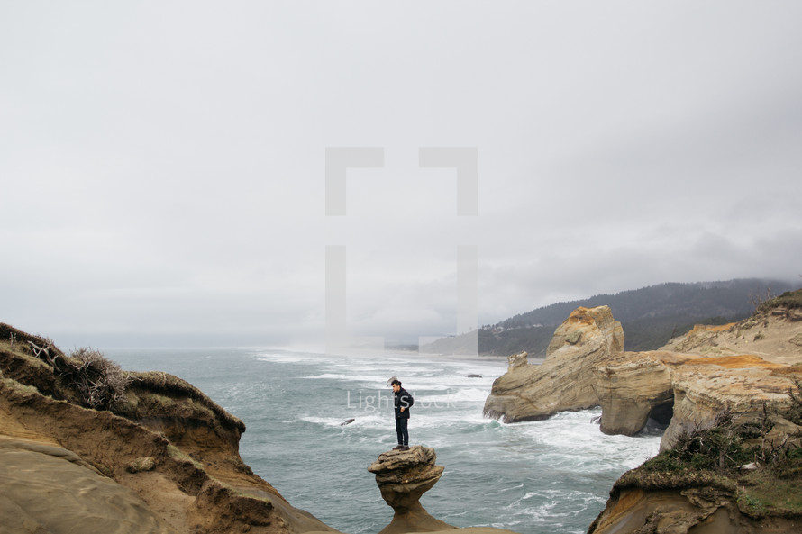 a man standing alone on a rock formation near the ocean 