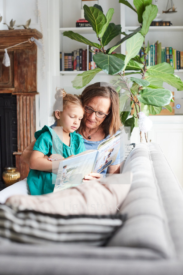a grandmother reading a book to her granddaughter 
