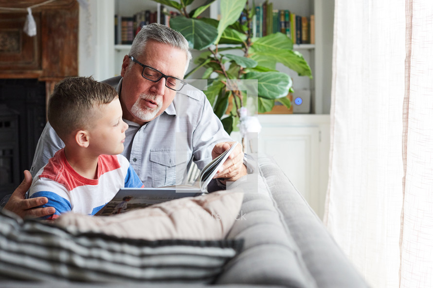 a grandfather reading a book to his grandson 