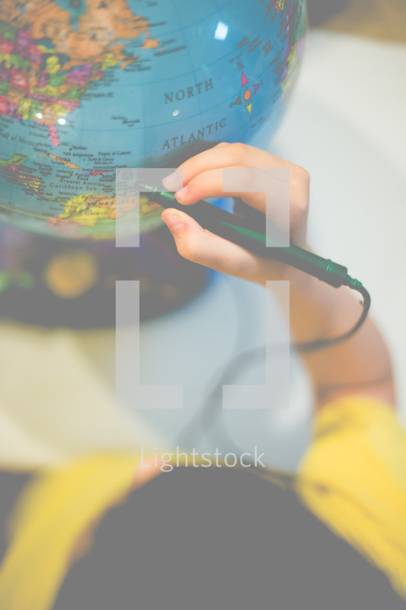 boy child pointing to a globe 