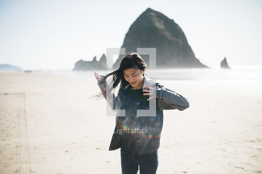 woman standing on a beach in a jacket 