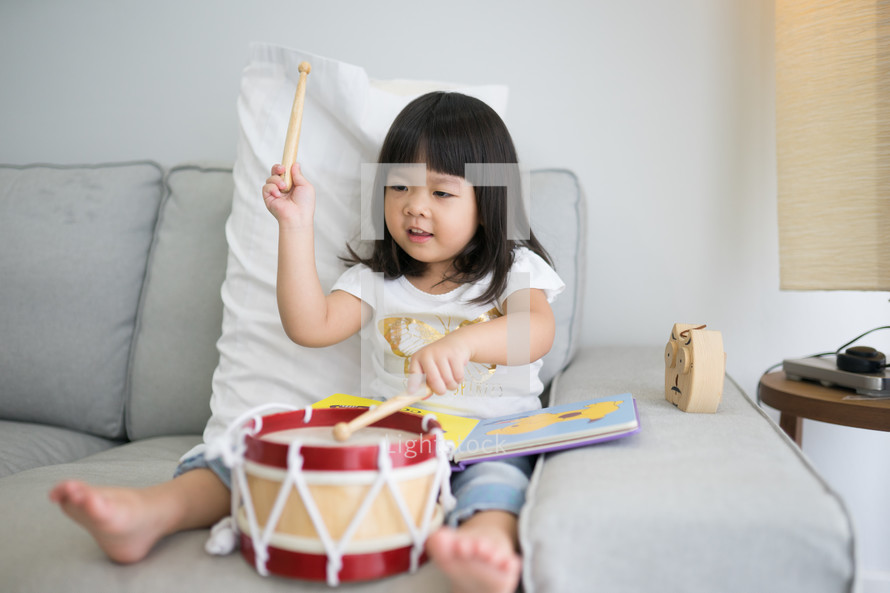 a toddler girl playing with a toy drum 