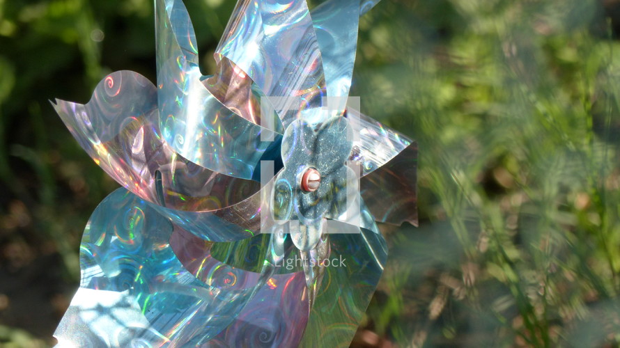 closeup of a pinwheel outdoors with sun shining on it and a blurred background