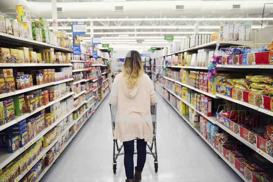 a woman pushing a shopping cart through a grocery store