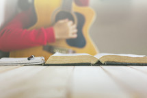 a person playing a guitar and reading a Bible 