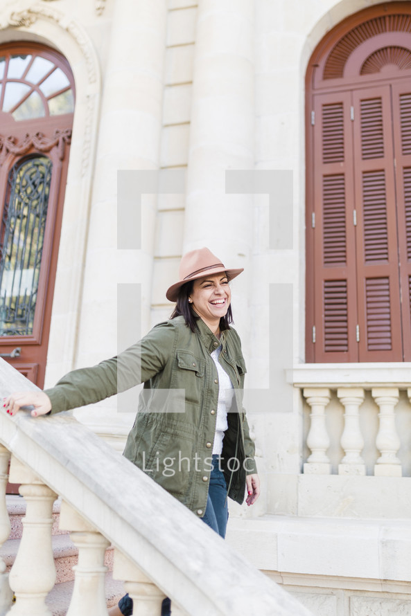 Portrait of a woman walking down the steps of a building smiling.