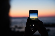 person taking pictures at sunset