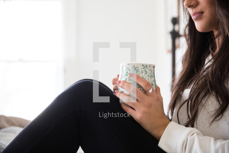 woman sitting in quiet meditation with a mug in her lap 