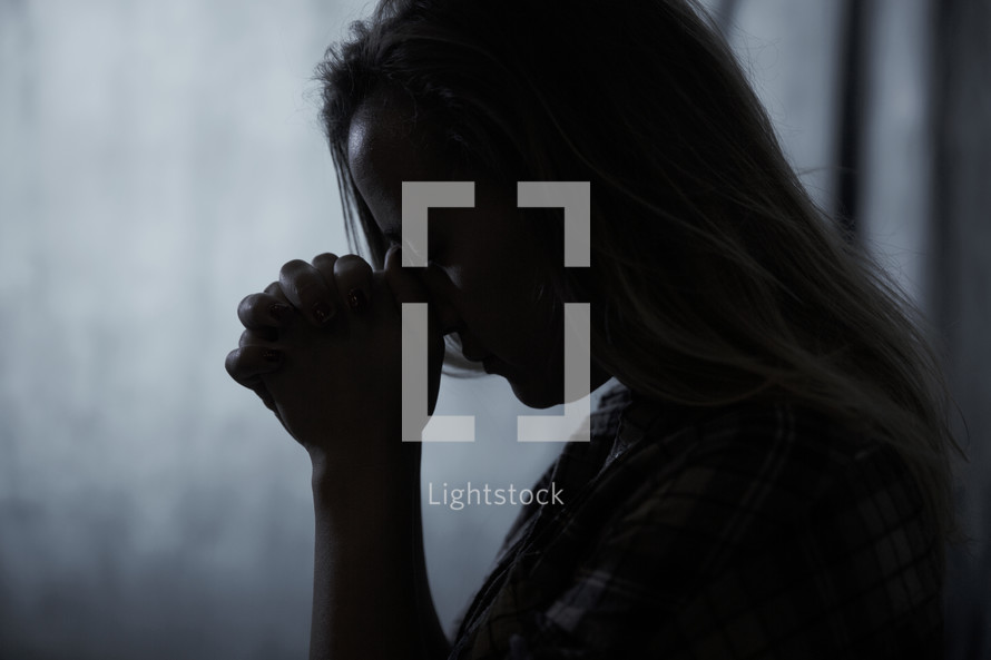 a woman praying in darkness 