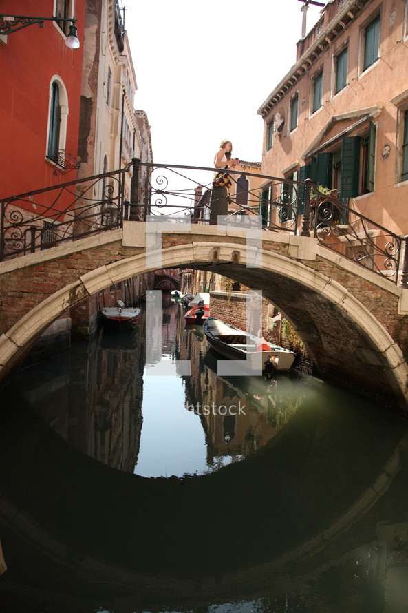 woman standing on a bridge over a canal in Venice 