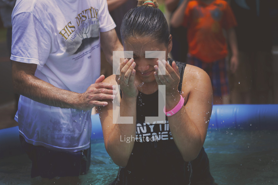 A young woman rises from a baptismal pool.