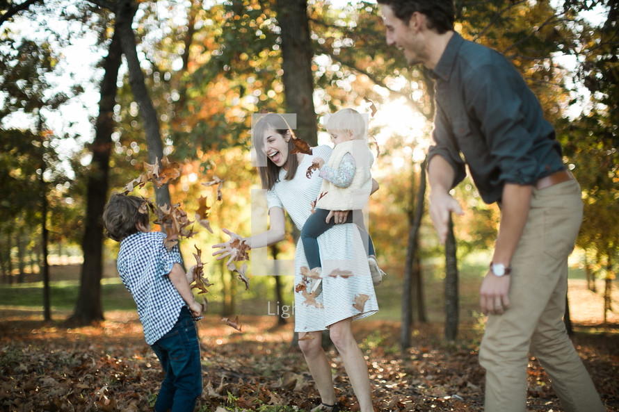 a young family playing in fall leaves 