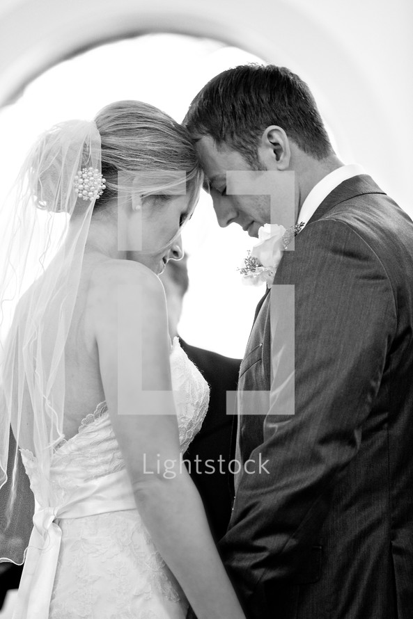 Bride and groom praying together at wedding alter