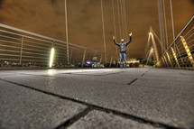 Man on bridge with hands raised