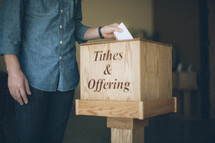 Man putting envelope into a tithes and offering box