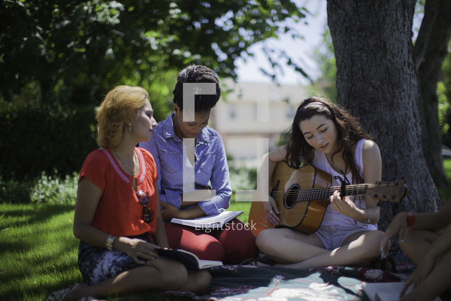 woman's group Bible study outdoors with music from a guitar 