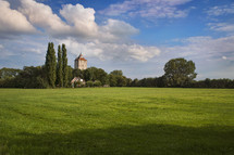 Green meadow and old tower at the end of the field