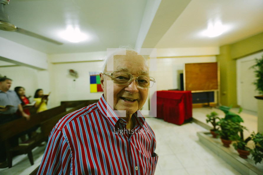 An elderly man greeting people in church 