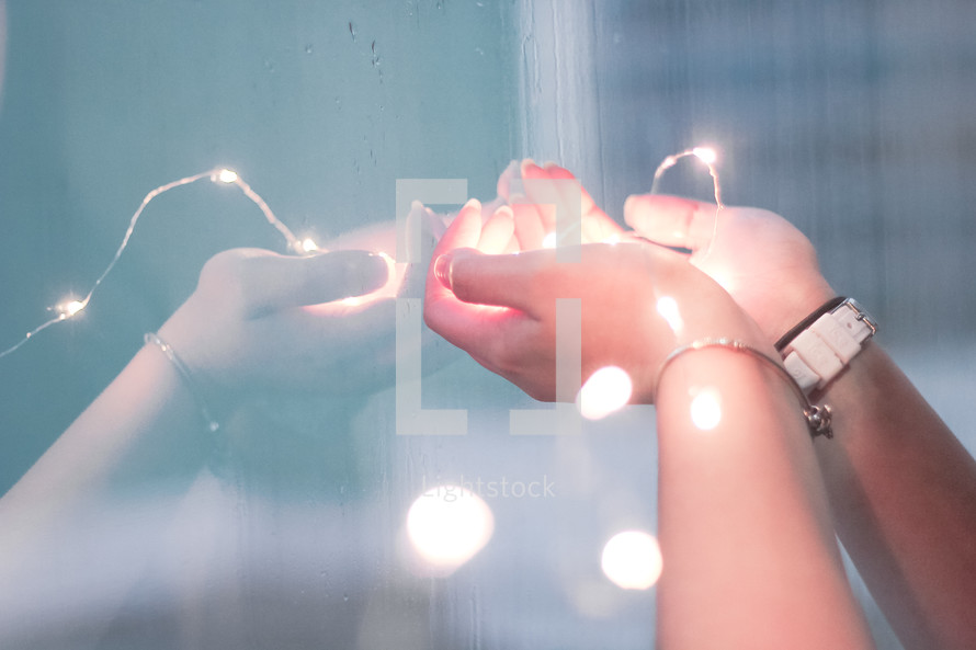 a woman holding fairy lights in her hands 