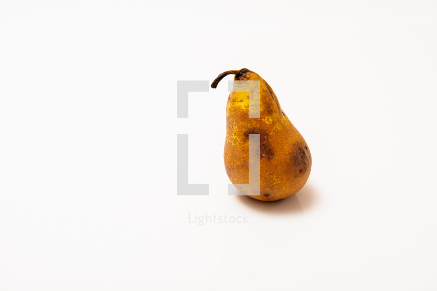 overripe pear with dark spots on a white background