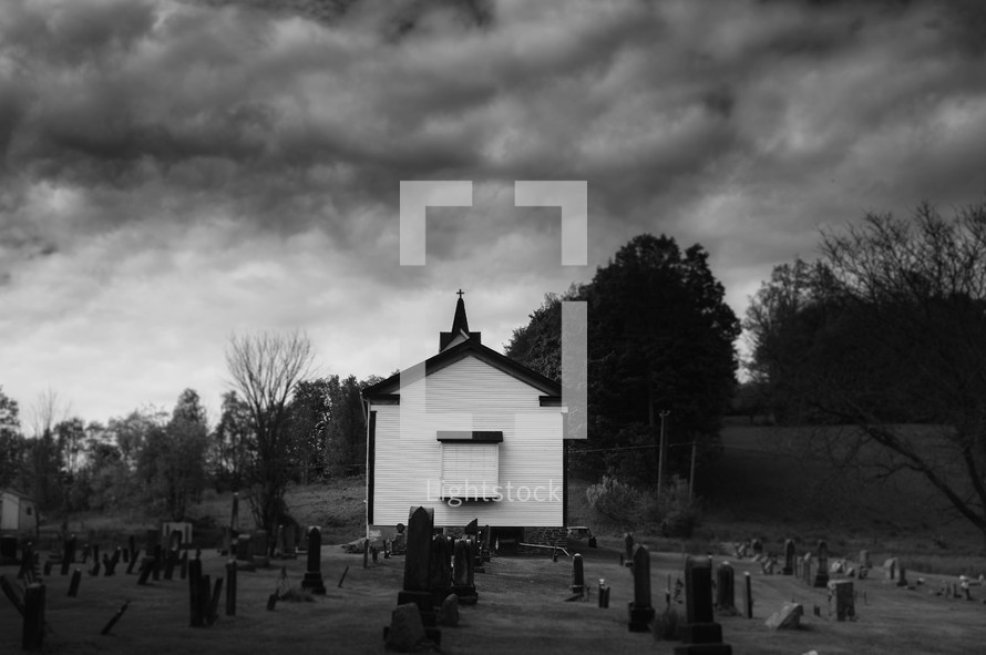 small white chapel and cemetery under cloudy skies 
