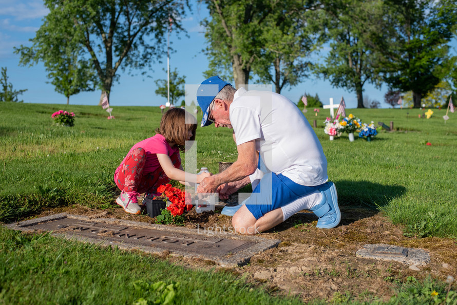 grandfather and granddaughter visiting a grave 