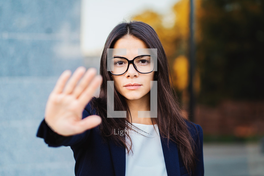 Portrait of young businesswoman disapproval gesture with hand: denial sign, no sign, negative gesture, professional female manager wearing glasses and suit.
