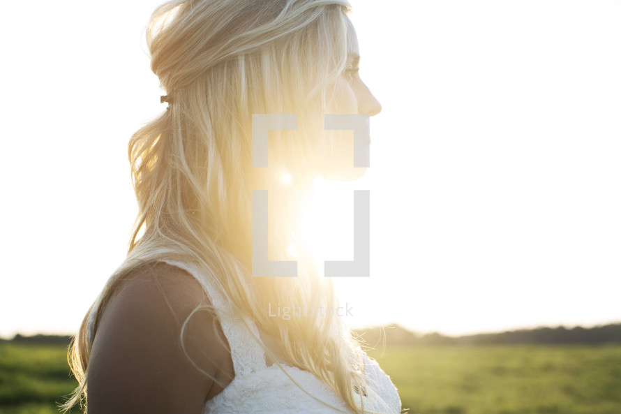 beautiful bride looking away in thought under intense sunlight. 